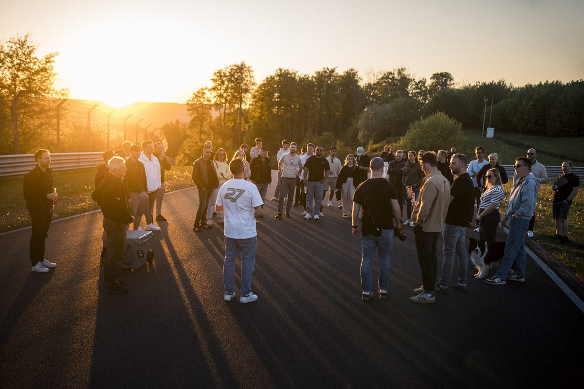 Participants réunis en cercle sur la piste au coucher du soleil, un verre à la main