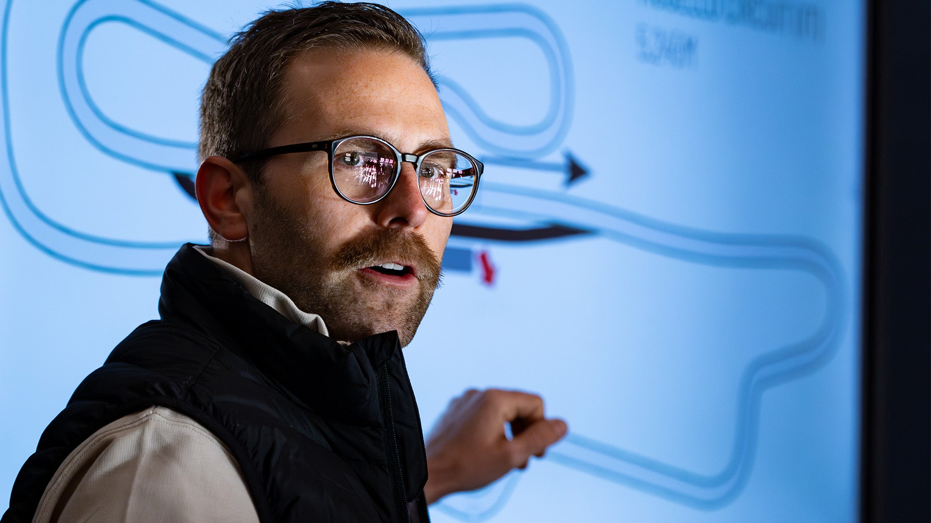 Pascal Pregizer, Motorsport-Coach von TWENTYSEVEN Trackdays, erklärt die Idealline vor einer Streckenkarte.