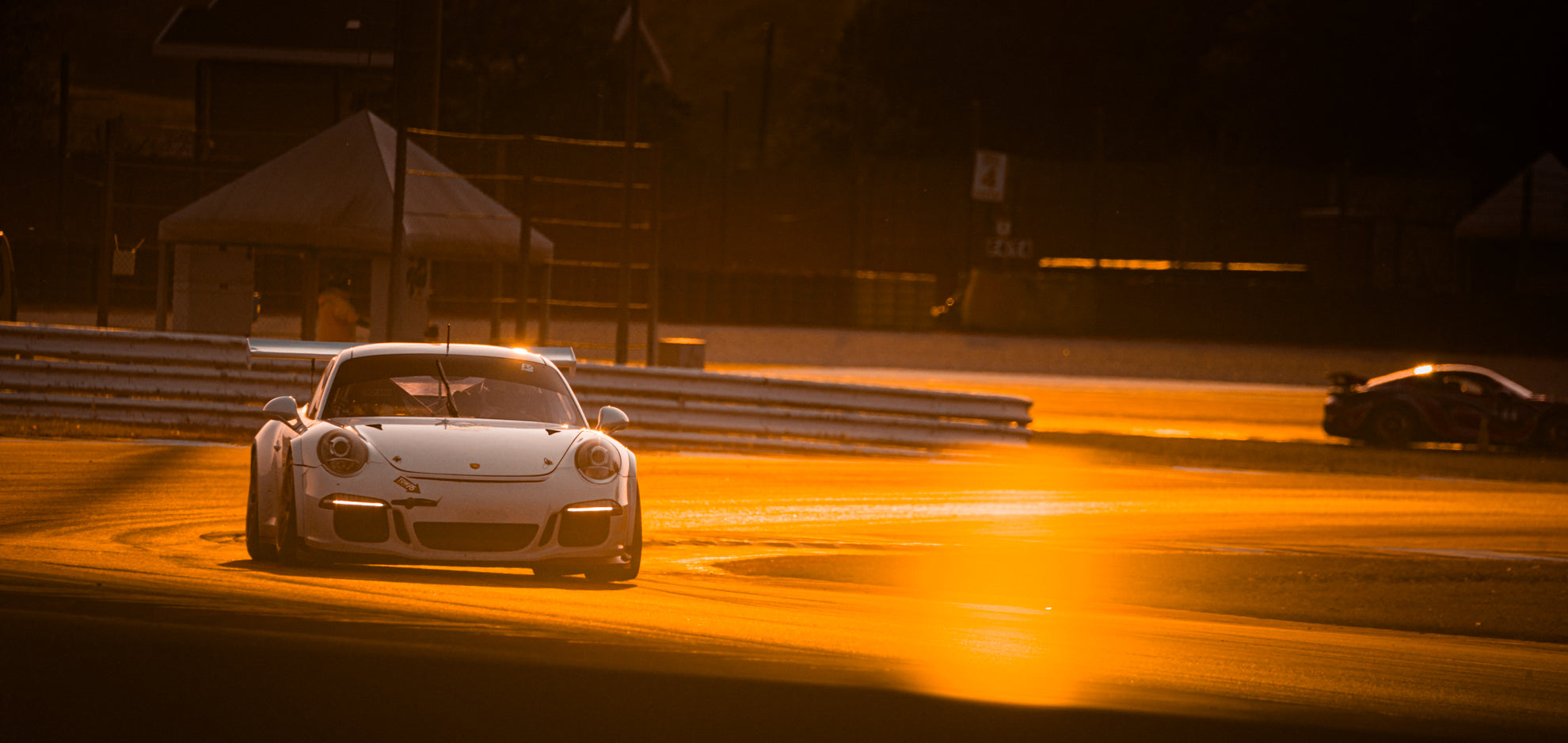 Weißer Porsche 991.2 GT3 Cup bei einem Test auf einer Rennstrecke, als bei Sonnenaufgang.