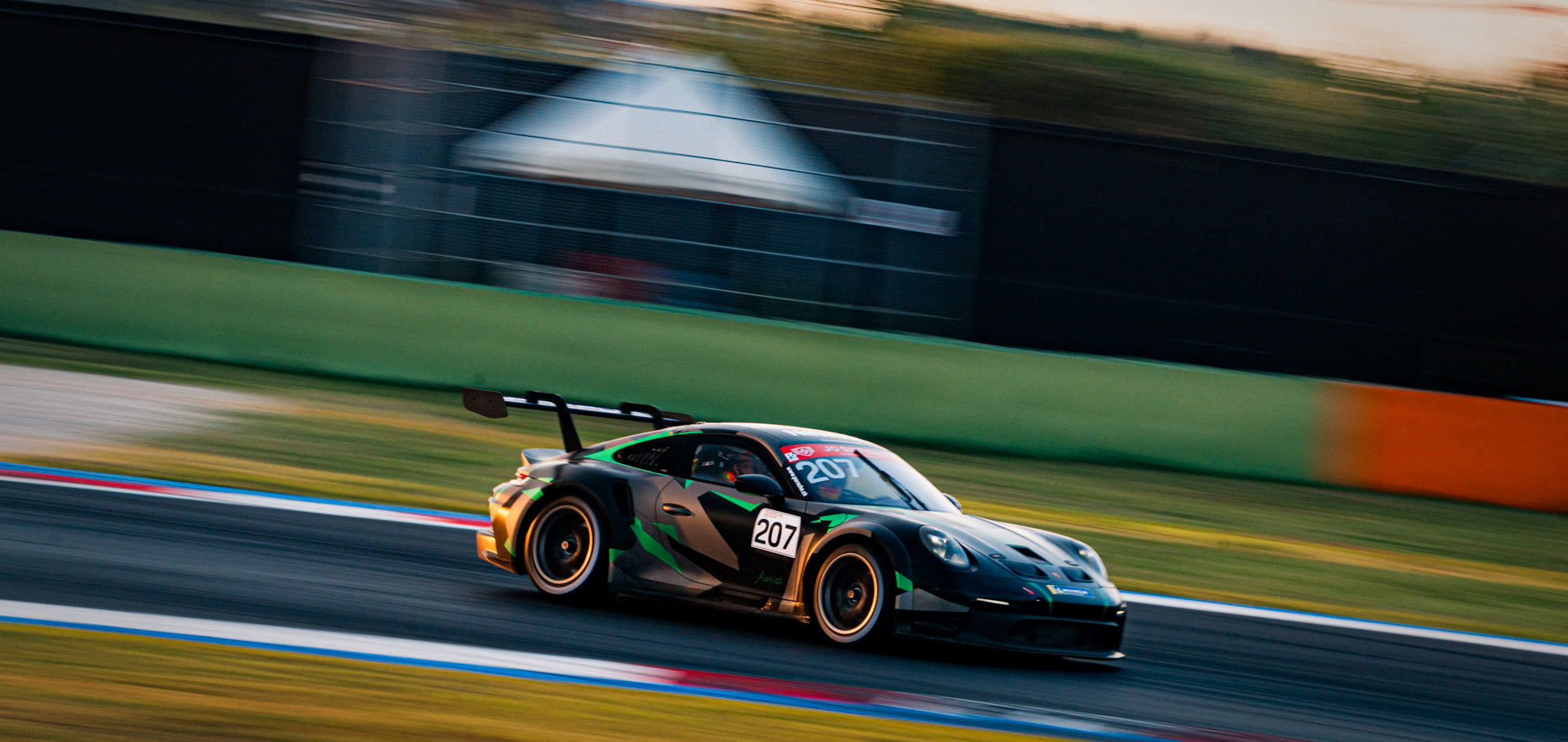 Grün-schwarzer Porsche 992 GT3 Cup mit Startnummer 207 und goldenen Rädern auf der Idealline des Misano World Circuit bei einem Racetest.