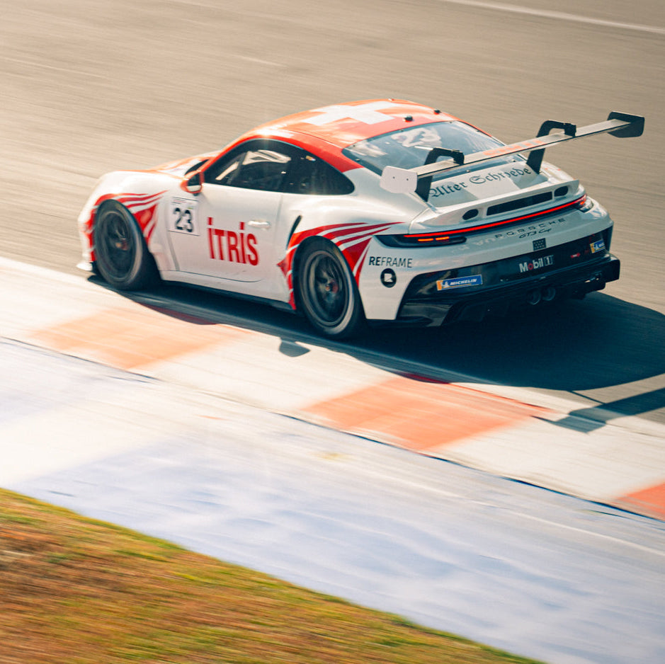 Weißer Porsche 992 GT3 Cup mit roter ITRIS-Lackierung und Startnummer 23 in der Heckansicht an einem Curb des Misano World Circuit.