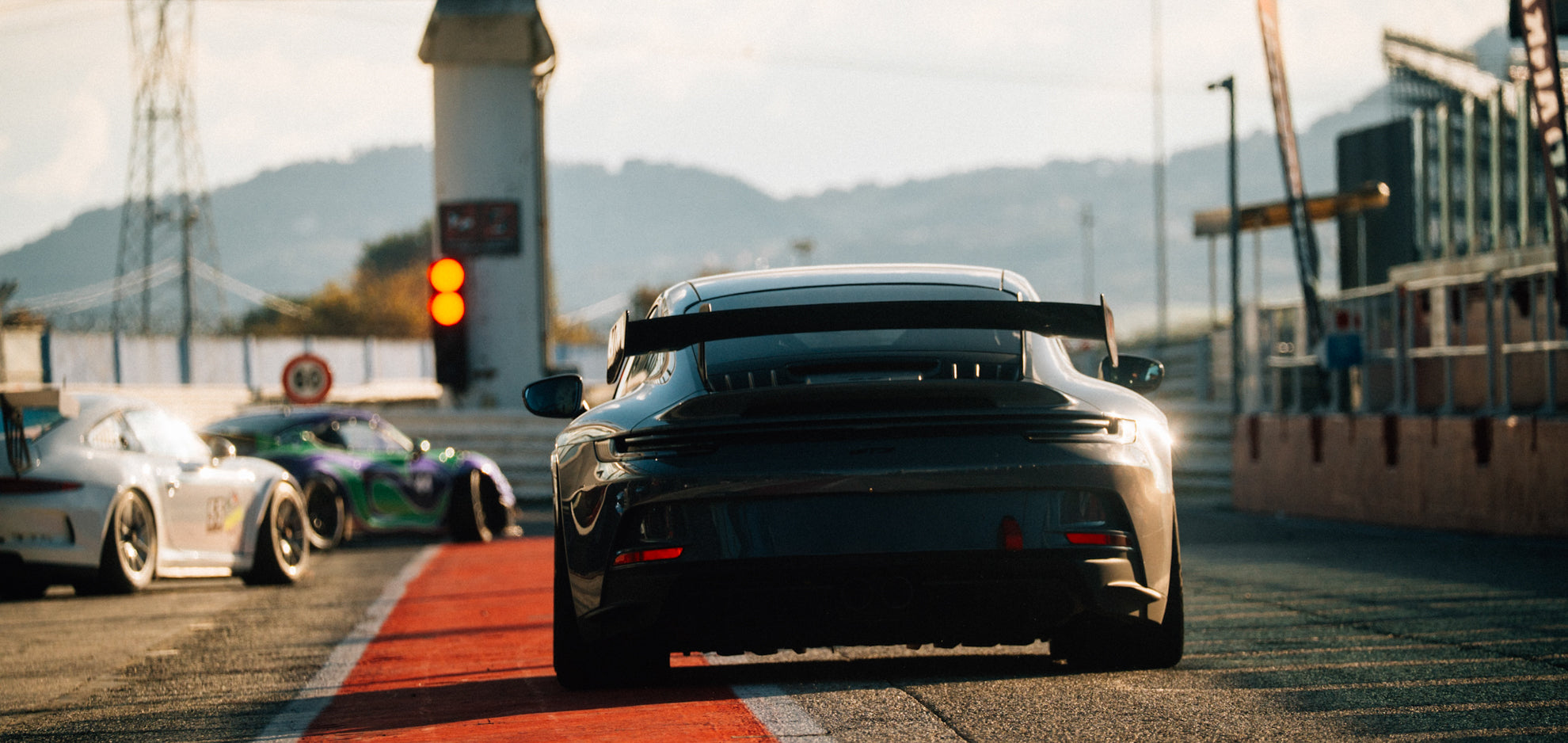 Mehrere Sportwagen in der Boxengasse des Misano World Circuit beim Trackday – im Vordergrund ein dunkler Porsche 992 GT3 in Heckansicht.