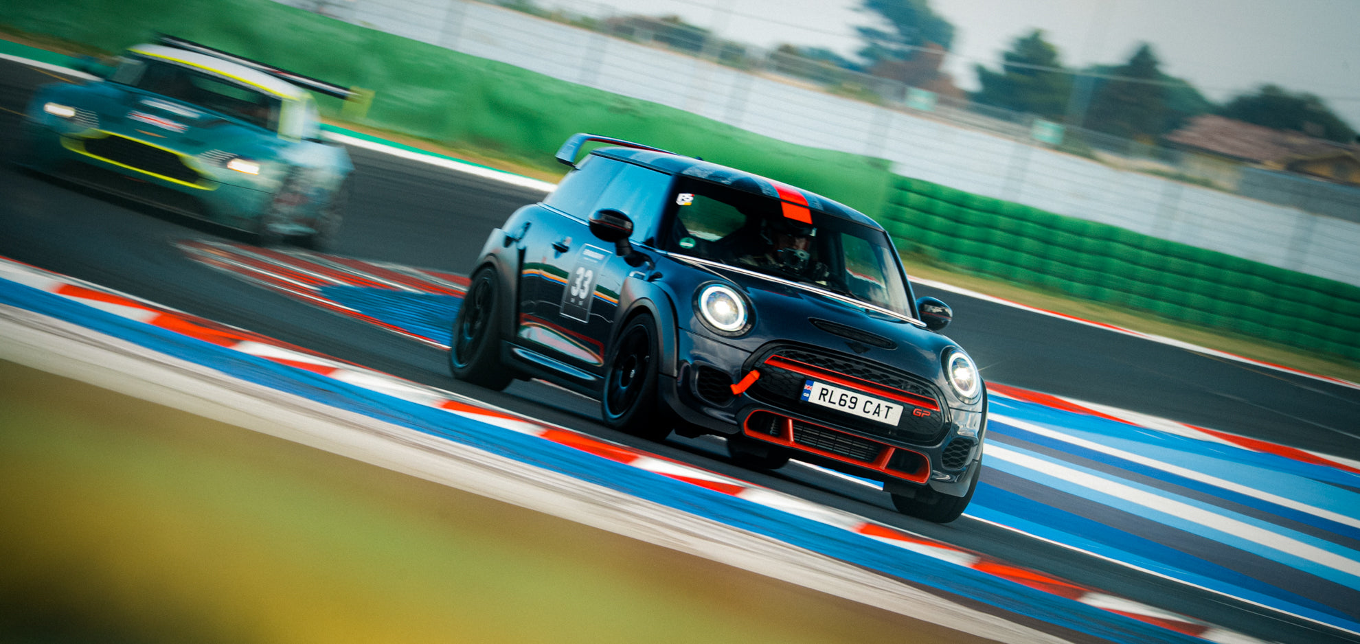 Schwarzer Mini GP3 mit Startnummer 33 auf Semislicks vor einem Aston Martin Vantage GT4 auf dem Misano World Circuit beim Trackday.