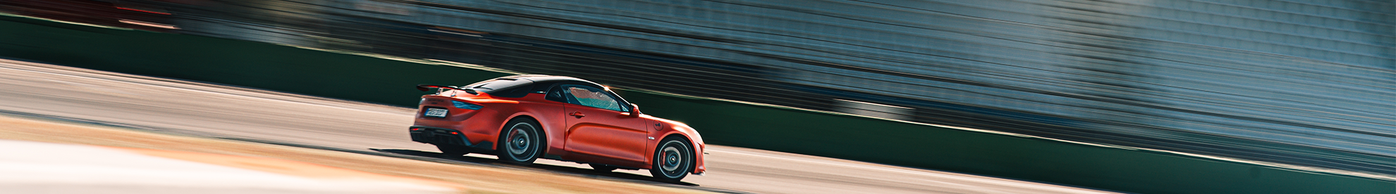 Orangene Alpine A110 auf einer Rennstrecke während eines Trackdays.