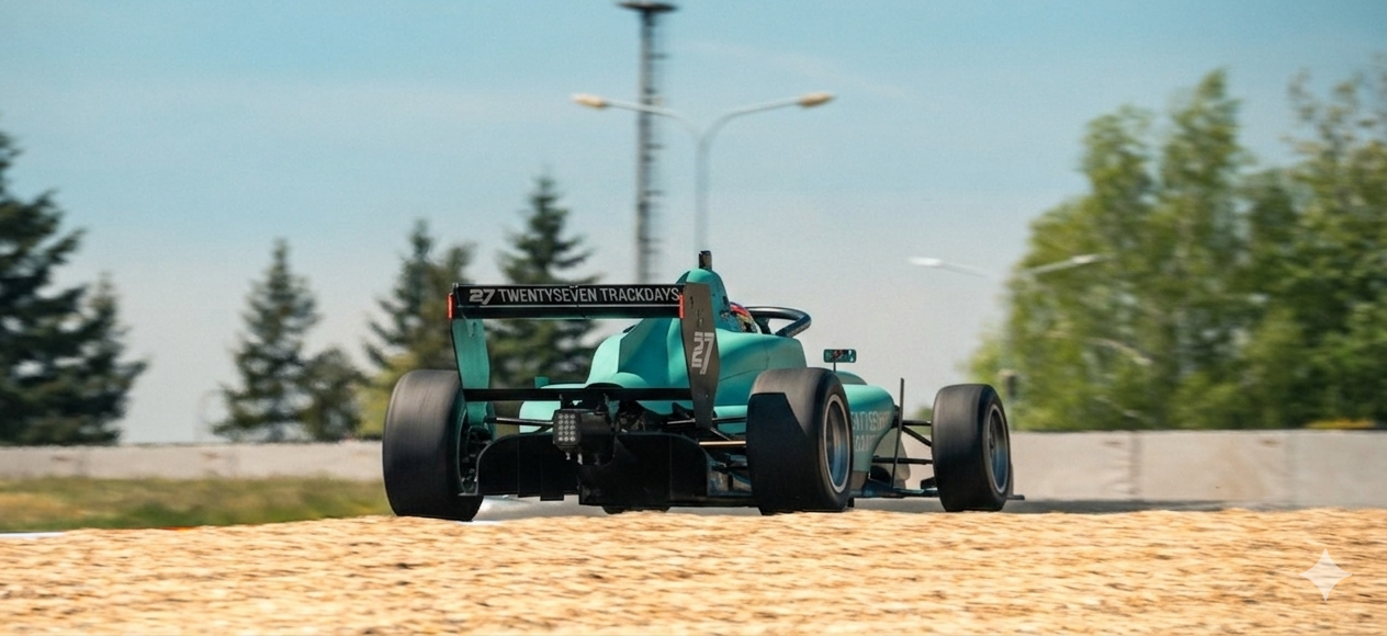 Türkiser Formel-3 Wagen mit TWENTYSEVEN TRACKDAYS Branding in Heckansicht auf dem Kiesbett des Automotodrom Brno bei einem Testtag.