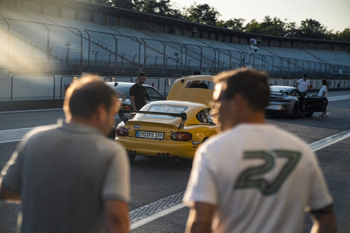 Participants and sports cars in the Hockenheimring pit lane in the evening light at a TWENTYSEVEN Afterwork Trackday