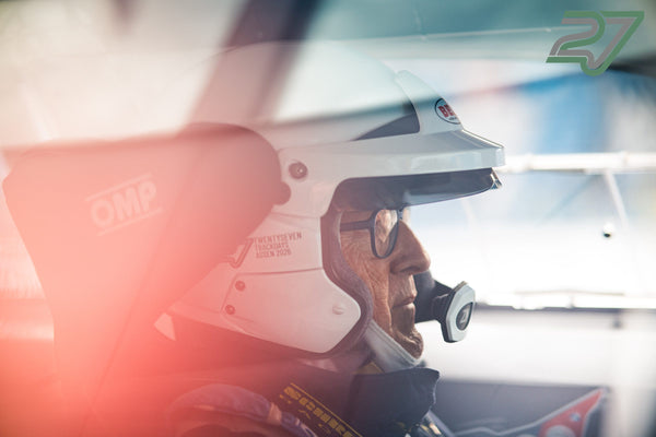Ein Fahrer im Helm sitzt im Profil, rotes Gegenlicht durchflutet das Cockpit