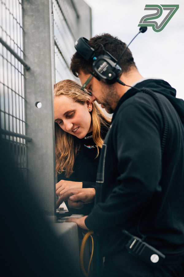 Zwei Streckenposten mit Headset beugen sich konzentriert über ein Gerät am Zaun