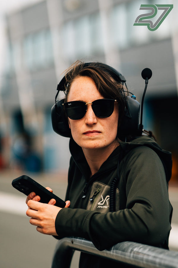 Eine Mitarbeiterin mit Sonnenbrille und Headset blickt in Assen aufmerksam vom Smartphone auf
