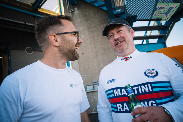 Zwei Männer im Gespräch, einer im Martini-Racing-Shirt mit einer Flasche Peroni in der Hand