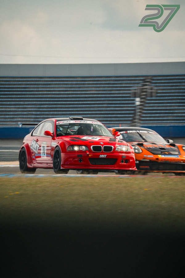Roter BMW M3 setzt sich knapp vor einem orangefarbenen Porsche durch die Kurve ab