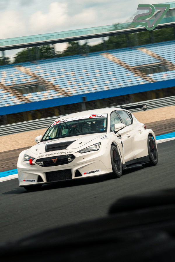 Weißer Cupra TCR mit kupferfarbenem Logo nähert sich schräg von vorn, aufgenommen aus sehr niedrigem Kamerawinkel