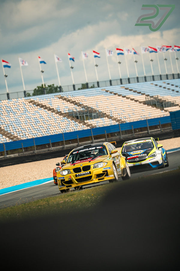 Goldfarbener BMW-Rennwagen führt in der Sonne vor einem weiß-grünen Opel Astra auf dem TT Circuit Assen