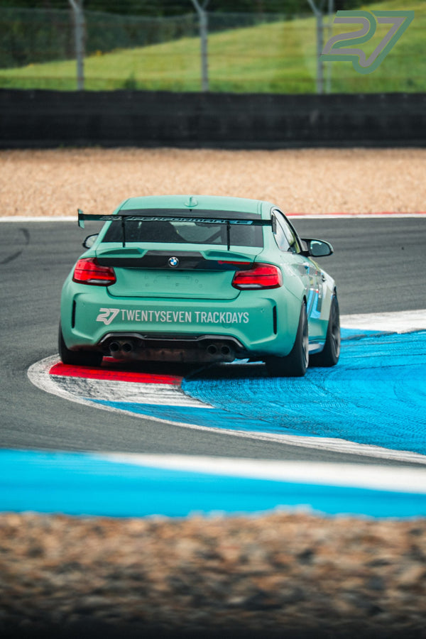 Mintgrüner BMW M2 mit Twentyseven-Trackdays-Schriftzug am Heck neigt sich in die Kurve