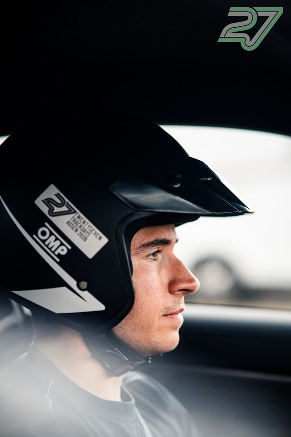 Ein Fahrer im Helm blickt konzentriert nach vorn, Profilaufnahme durch die Frontscheibe