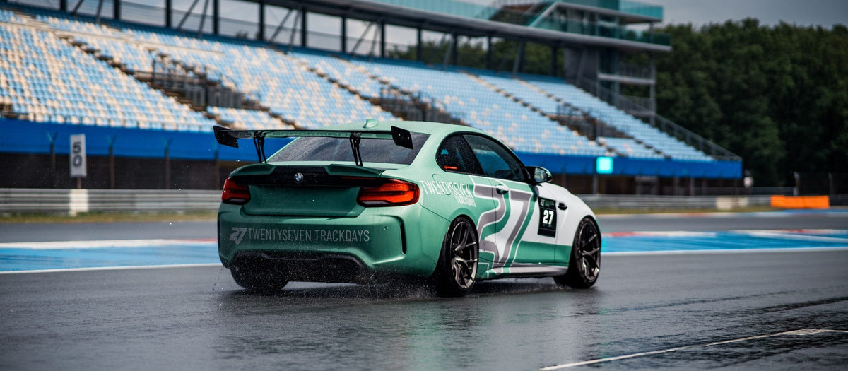 Mintgrüner BMW M2 mit Trackdays-Schriftzug zieht in Assen auf nasser Strecke eine Wasserfahne