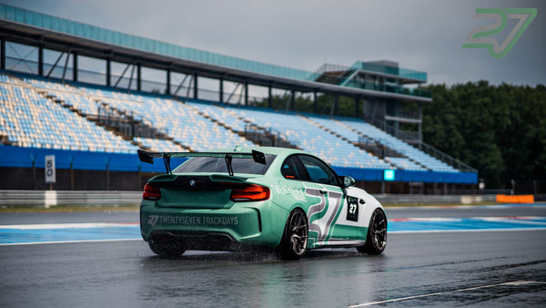 Mintgrüner BMW M2 mit Trackdays-Schriftzug zieht in Assen auf nasser Strecke eine Wasserfahne