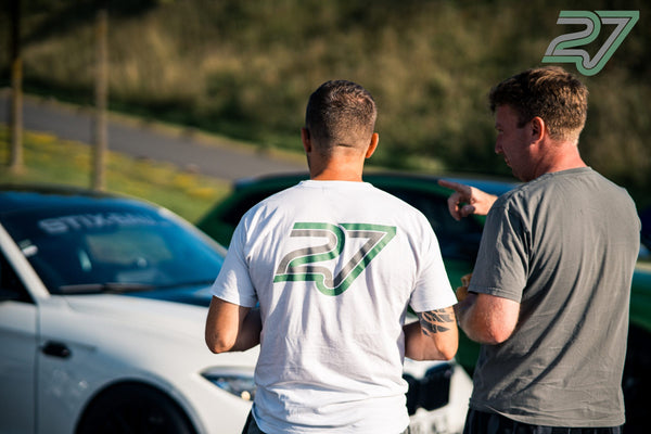 Zwei Männer unterhalten sich am Streckenrand, im Hintergrund parken mehrere Fahrzeuge