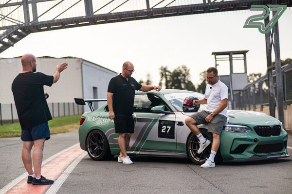 Drei Männer stehen an einem salbeigrünen BMW M2 mit Startnummer 27, einer sitzt auf dem vorderen Kotflügel