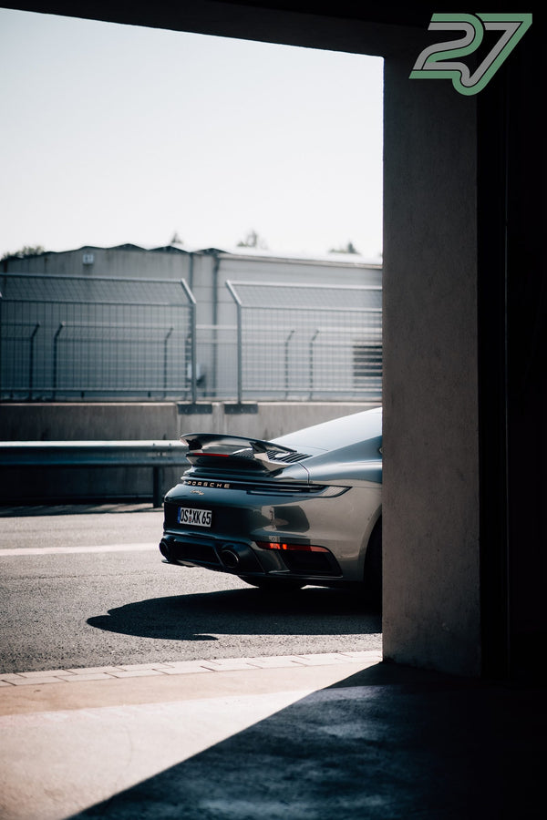 Grauer Porsche 911 fährt im grellen Sonnenlicht vorbei, gerahmt durch einen dunklen Türdurchgang