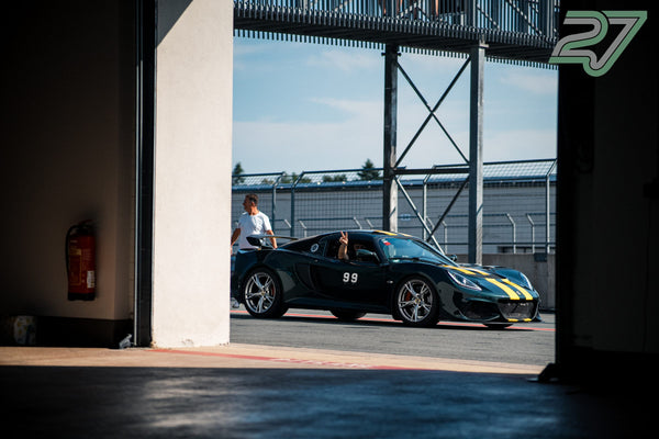 Ein dunkelgrüner Lotus mit gelben Streifen rollt aus der Box, der Fahrer zeigt ein Peace-Zeichen