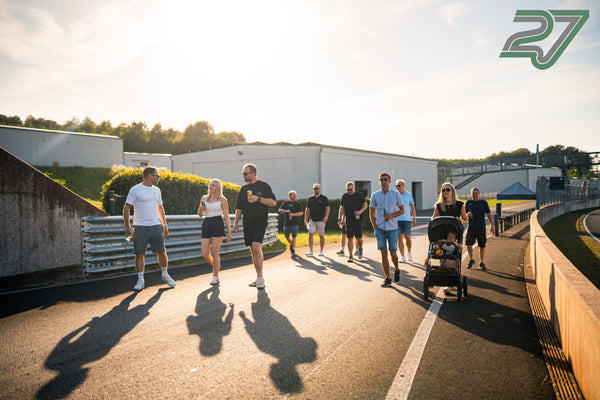Eine Gruppe mit Kinderwagen geht im Gegenlicht über die Strecke des Bilster Berg, lange Schatten am Boden