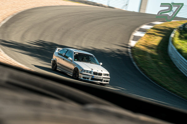 Ein silberfarbener BMW mit Startnummer 72 zieht durch eine weite Kurve, der Hintergrund verwischt