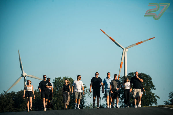 Eine Gruppe geht bei Sonnenschein auf die Kamera zu, hinter ihnen drehen sich zwei Windräder am Bilster Berg