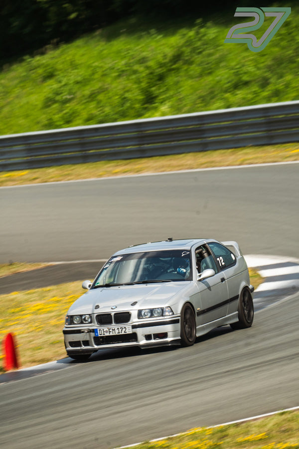Ein silberner BMW E36 Compact mit Überrollkäfig und Startnummer 72 fährt eng um einen Pylon
