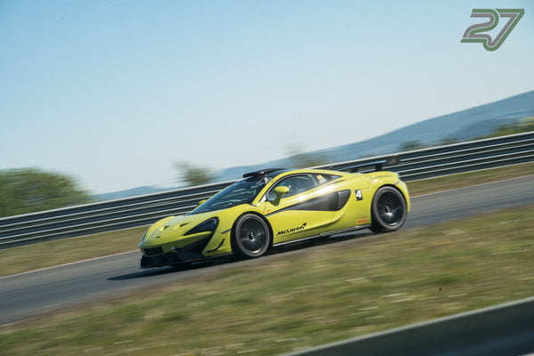 Gelbgrüner McLaren mit großem Heckflügel neigt sich seitlich durch eine schnelle Kurve