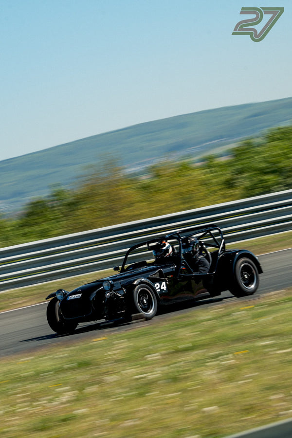 Schwarzer offener Rennwagen mit Überrollkäfig neigt sich beim Trackday durch eine Kurve
