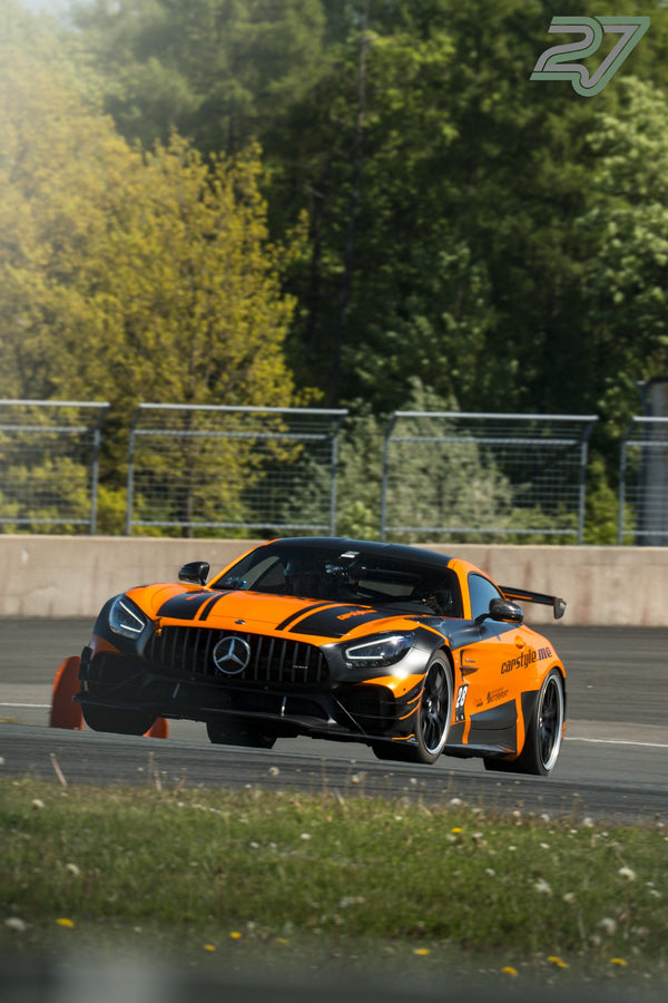 Oranger Mercedes-AMG GT neigt sich beim Trackday in schneller Kurvenfahrt am Randstein