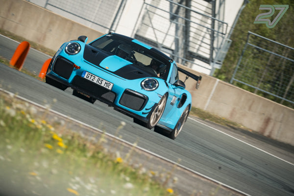 Hellblauer Porsche mit schwarzer Motorhaube und großem Heckflügel aus niedrigem Blickwinkel