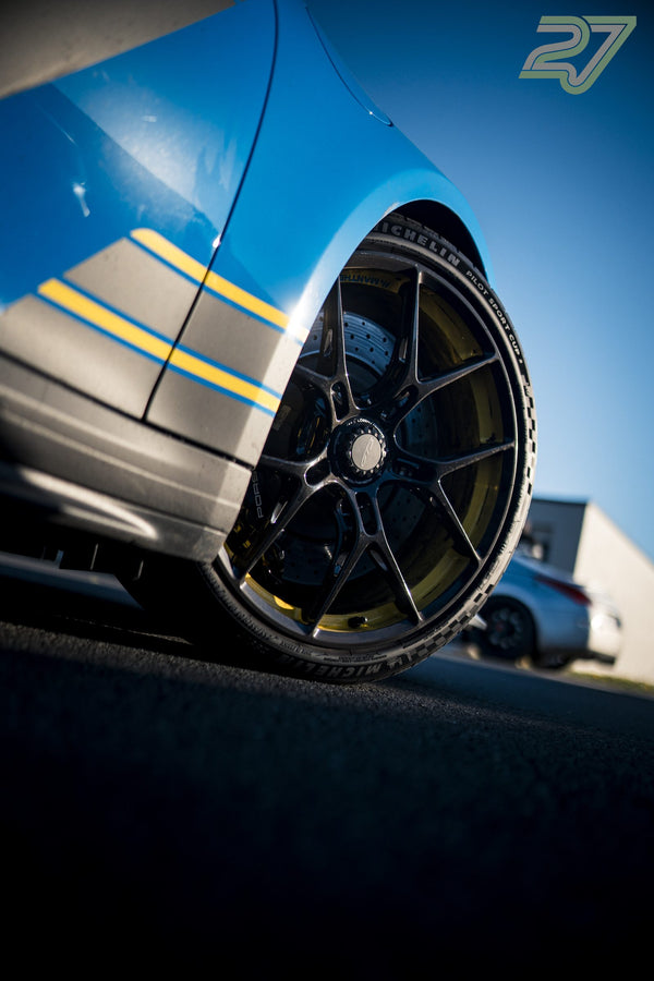 Rennstreifen und ein filigranes Leichtmetallrad zieren einen blauen Porsche beim Trackday