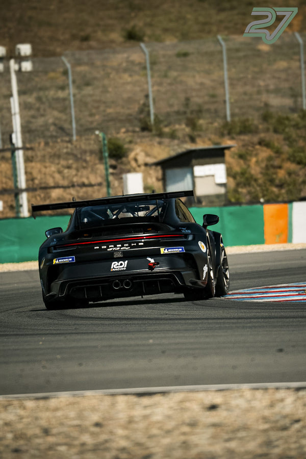 Schwarzer Porsche 911 GT3 Cup mit großem Heckflügel fährt aus einer engen Steilkurve in Brünn heraus