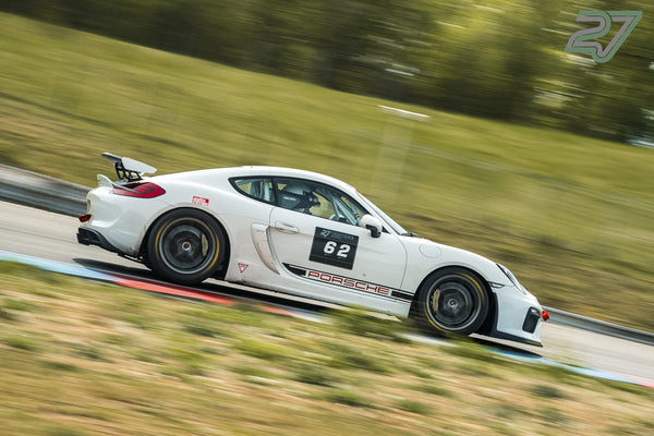 Weißer Porsche Cayman GT4 mit Startnummer 62 fährt in Seitenansicht mit sichtbaren goldenen Bremssätteln