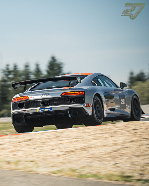 Grau-oranger Audi R8 GT3 mit Startnummer 28 fährt heckseitig über den Randstein hinaus