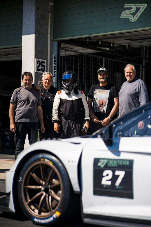 Fünf Männer posieren neben einem weißen Audi R8 GT3 vor der geöffneten Boxengarage in Brünn