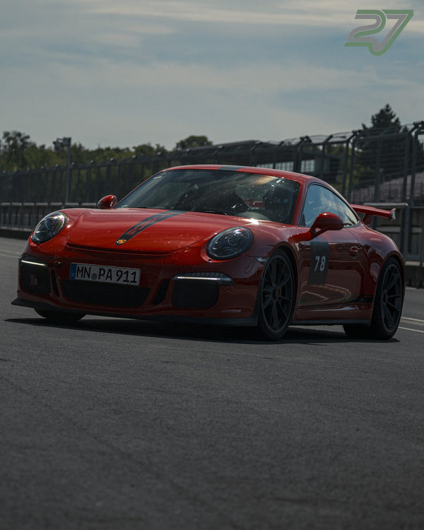 Roter Porsche 911 mit Startnummer 78 fährt frontal in Schräglage über die Strecke