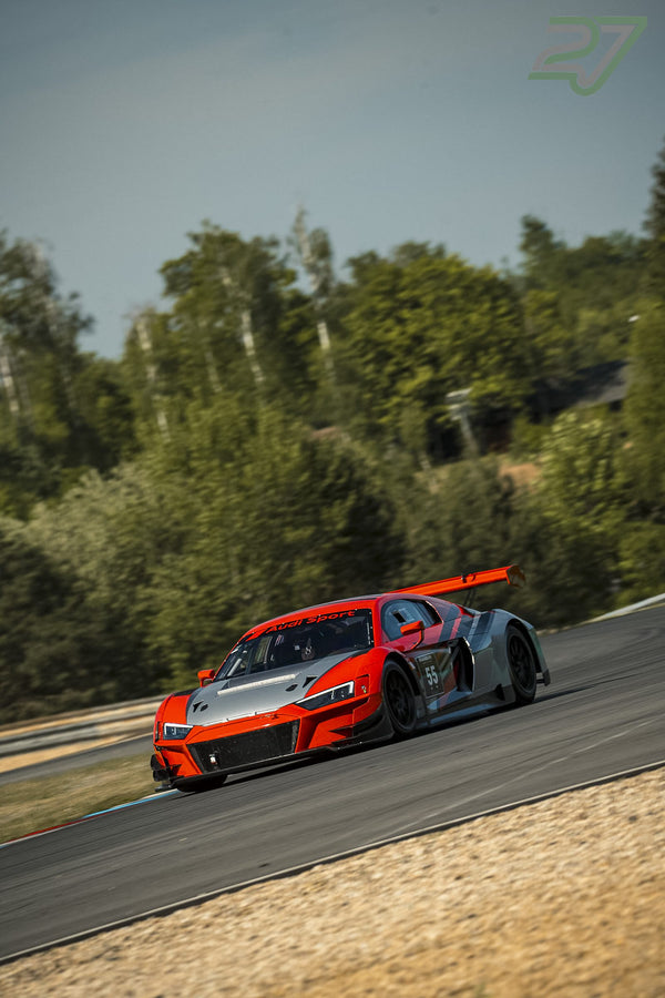 Orange-grauer Audi R8 GT3 mit Startnummer 55 fährt dicht an Bäumen vorbei aus der Kurve