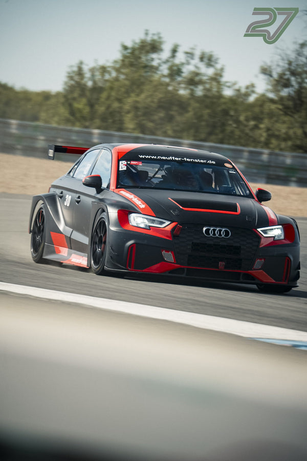 Schwarz-roter Audi RS3 LMS fährt mit eingeschaltetem Scheinwerferlicht frontal auf die Kamera zu