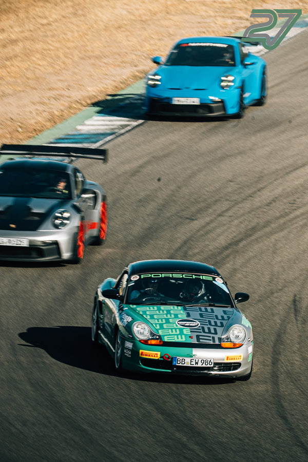 Drei Porsche fahren hintereinander durch eine Kurve am Hockenheimring: grün, silbern-rot und türkis lackiert
