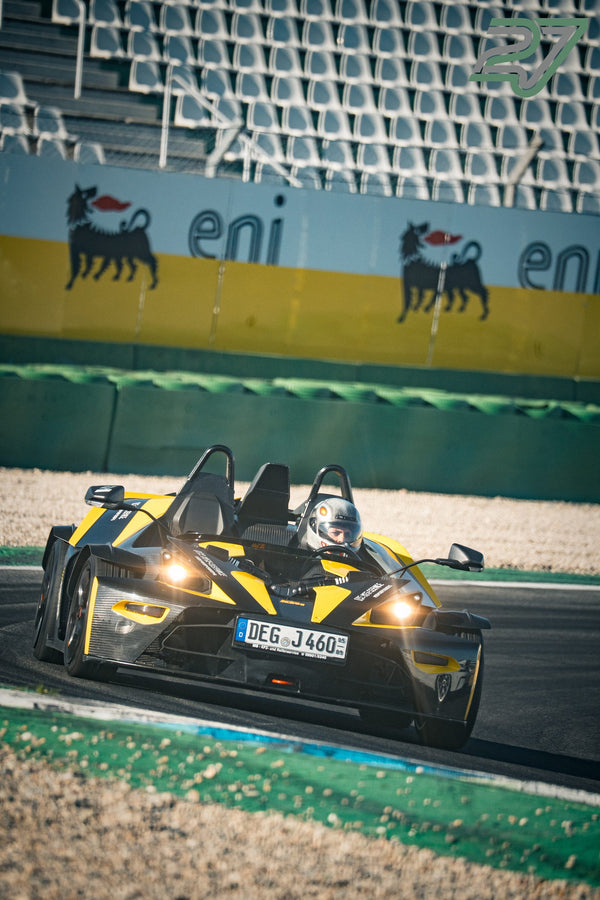Gelb-schwarzer KTM X-Bow mit Scheinwerferlicht fährt im offenen Cockpit durch eine Kurve am Hockenheimring