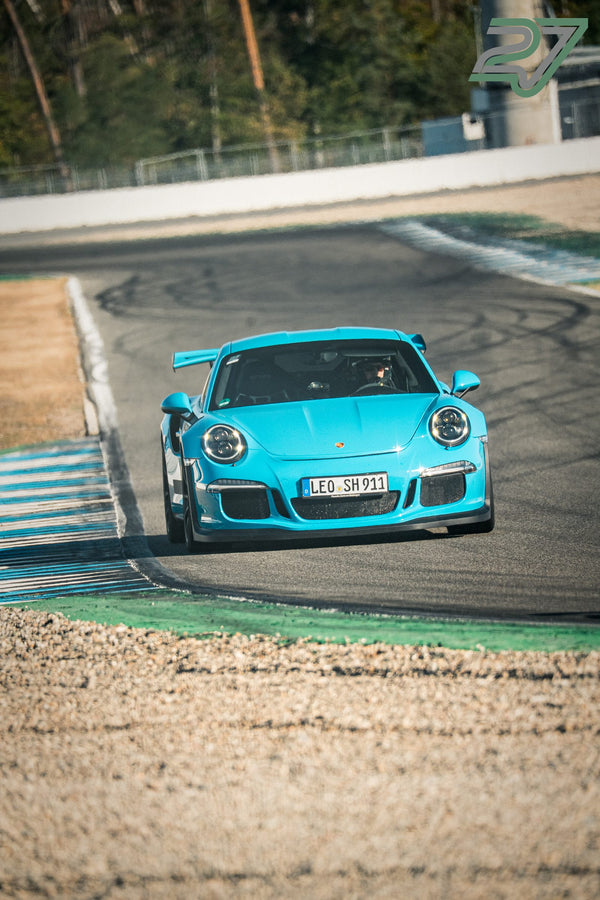 Türkisfarbener Porsche 911 GT3 mit Heckflügel nähert sich frontal der Kamera in einer Kurve