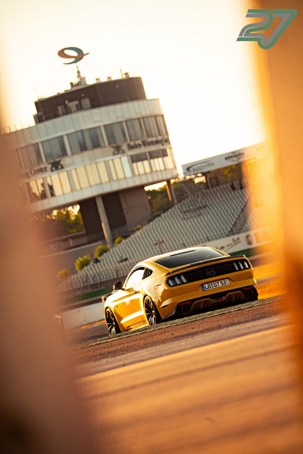 Gelber Ford Mustang wartet im Gegenlicht der Abendsonne vor dem Boxengebäude des Hockenheimrings
