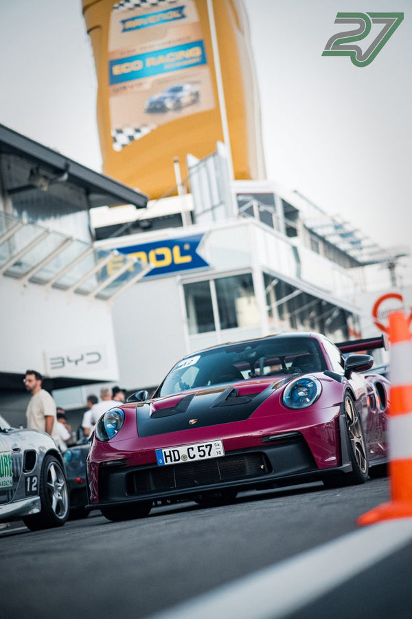 Bordeauxroter Porsche 911 GT3 rollt frontal durch die Boxengasse des Hockenheimrings, Menschen daneben