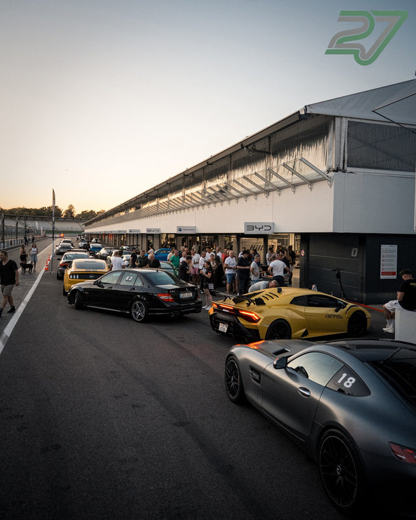 Graue Mercedes-AMG GT und gelber Lamborghini Huracán stehen nebeneinander im abendlichen Fahrerlager