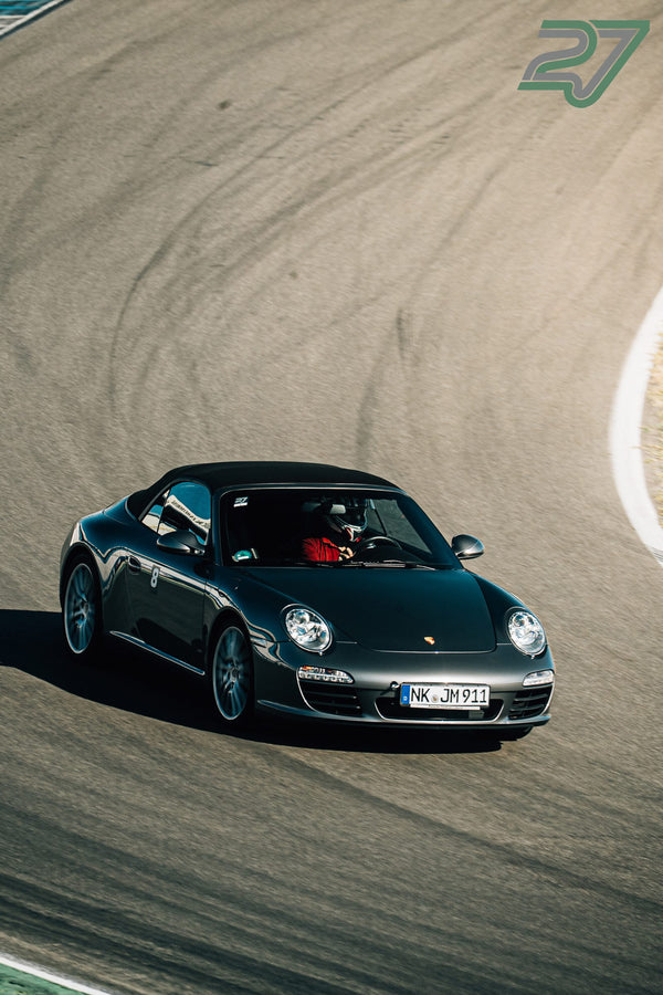 Dunkelgraues Porsche 911 Cabrio zieht aus der Vogelperspektive durch eine Kurve am Hockenheimring