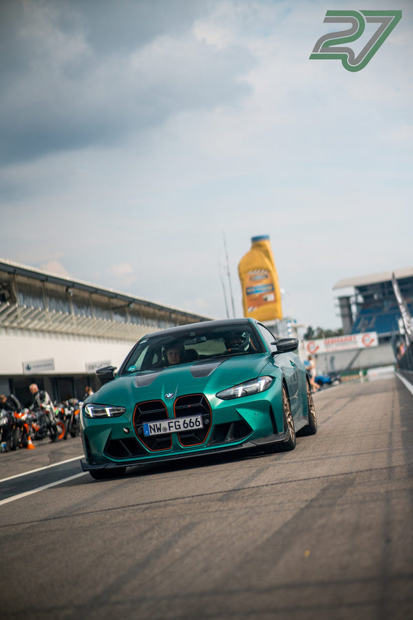 Dunkelgrüner BMW M4 mit orangefarbenen Akzenten fährt aus der Boxengasse auf die Strecke