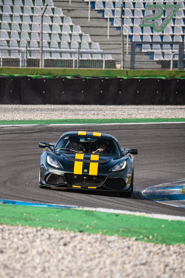 Dunkelgrüner Lotus mit gelben Rennstreifen biegt mit sichtbarem Fahrer in eine Kurve am Hockenheimring